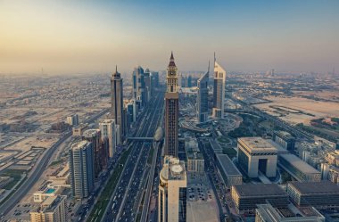 Gökdelenler ve gün batımında büyük bir modern şehrin karayolları. Dubai şehir merkezinde panoramik manzara, Birleşik Arap Emirlikleri.