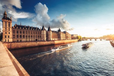 Paris, Fransa'da Seine nehri ve Conciergerie nehri üzerinde cruise tekneleri ve Pont Neuf ile dramatik gün batımı. Renkli seyahat arka planı. Romantik şehir manzarası.