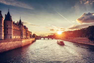Paris, Fransa, Conciergerie, Pont Neuf ve gün batımında cruise tekne ile güzel silueti. Renkli seyahat arka planı. Romantik şehir manzarası.