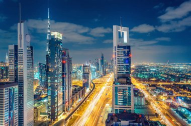 Büyük ve modern bir şehrin renkli gece silueti. Dubai, Birleşik Arap Emirlikleri. Otoyollarda ve gökdelenlerde havadan görünüm.