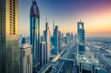 Gökdelenler ve gün batımında büyük bir modern şehrin karayolları. Dubai şehir merkezinde havadan görünüm, Birleşik Arap Emirlikleri.