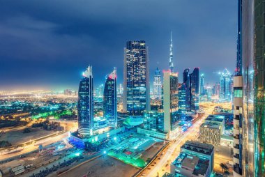Renkli şehir aydınlatmaları ile muhteşem kentsel siluet. Dubai, Birleşik Arap Emirlikleri otoyolları ve gökdelenlerinde havadan görünüm.