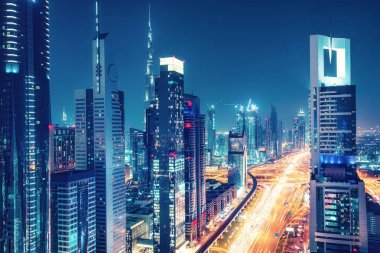 Işıklı gökdelenler ve otoyollar ile büyük bir modern şehrin renkli silueti. Dubai şehir merkezi, Bae üzerinde havadan görünümü. Seyahat ve mimari arka plan.