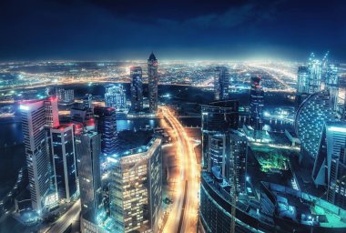 Büyük ve modern bir şehrin renkli gecelik silueti. Dubai, Birleşik Arap Emirlikleri. Otoyollarda ve gökdelenlerde havadan görünüm.