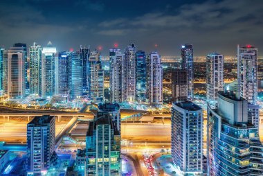 Büyük modern şehrin doğal gece silueti. Dubai Marina, Bae gökdelenler ve karayolları üzerinde havadan görünümü. Çok renkli seyahat arka planı.