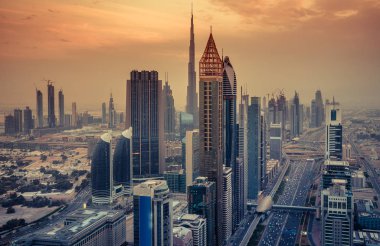 Gün batımında Dubai, Birleşik Arap Emirlikleri şehir merkezinin gökdelenleri ve otoyolları. Renkli ufuk çizgisi.