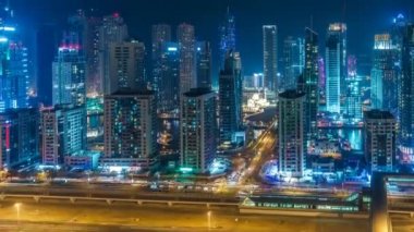 Dubai Marina'nın renkli silueti geceleyin. Gökdelenler ve otoyollar ile dere üzerinde Manzara yükseltilmiş görünümü. 4k zaman atlamalı