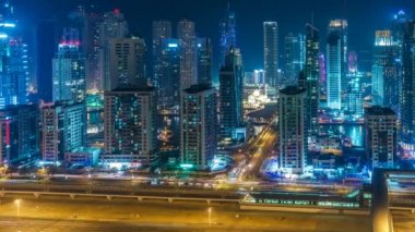 Dubai Marina'nın renkli silueti geceleyin. Gökdelenler ve otoyollar ile dere üzerinde Manzara yükseltilmiş görünümü. 4k zaman atlamalı