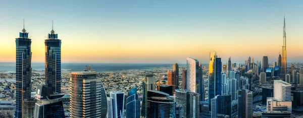 Scenic panorama view of Dubai's modern architecture at sunset. Colorful aerial skyline with downtown skyscrapers. Popular travel destination of the Middle East.