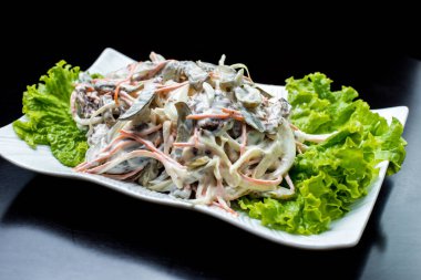 Çin mutfağı, salata, kızartılmış sığır eti, turşu, siyah bir arka plan üzerinde beyaz bir tabak içinde marul