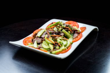 Çin mutfağı, siyah zemin üzerine beyaz tabak içinde salatalık ve domates ile sığır eti haşlama