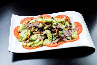 Çin mutfağı, siyah zemin üzerine beyaz tabak içinde salatalık ve domates ile sığır eti haşlama