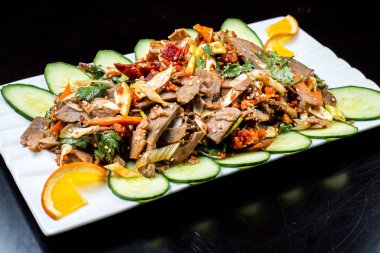 Çin mutfağı, siyah zemin üzerine beyaz tabak içinde salatalık ve domates ile sığır eti haşlama