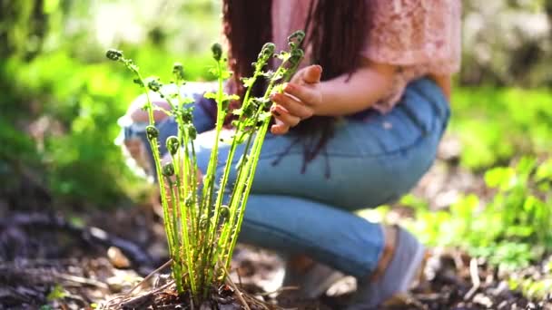 Menina vestida casual nova em óculos cheira flores sakura e sorri para a câmera. Concentre-se no conceito de primavera. Movimento lento . — Vídeo de Stock