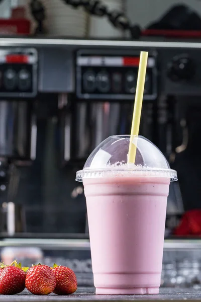 Strawberry milk shake to take away with straw on a dark background