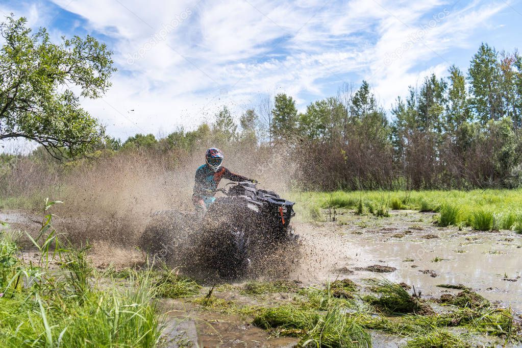 ATV Quad rides fast on big dirt and makes splashes of dirty water