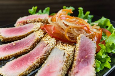 Natürmort otlar ve susam koyu gri yüzeyi ile kabuklu kavrulmuş orkinos biftek kadar kapatın