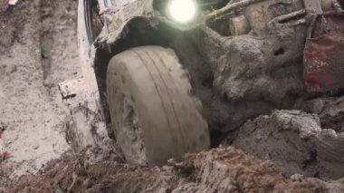 Bir araba tekerlek Close-up kirli su ve kir içinde sıkışmış. Tekerlek döner, ama onun çaresiz. Elektrikli Vinç çamur çeker