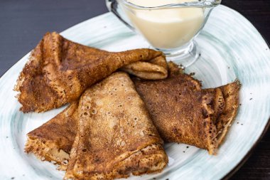 Ekşi krema ile bir tabakta krep yığını. Geleneksel Rus krep hafta için. Koyu arka plan