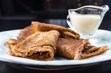 Ekşi krema ile bir tabakta krep yığını. Geleneksel Rus krep hafta için. Koyu arka plan