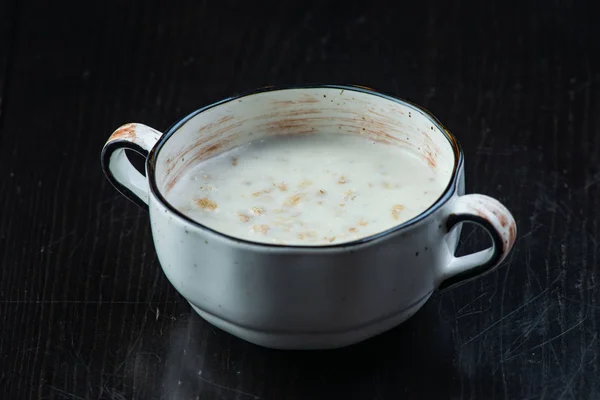 Micul dejun de dimineață, fulgi de ovăz pe lapte cu unt în farfurie albă pe fundal întunecat — Fotografie, imagine de stoc