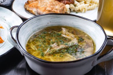 Tavuk suyuna çorba kase. Siyah ahşap bir masa üzerinde beyaz bir tabak içinde tavuk çorbası. Metin için özgür yer. Yukarıdan görüntüleyin. Üstten görünüm.