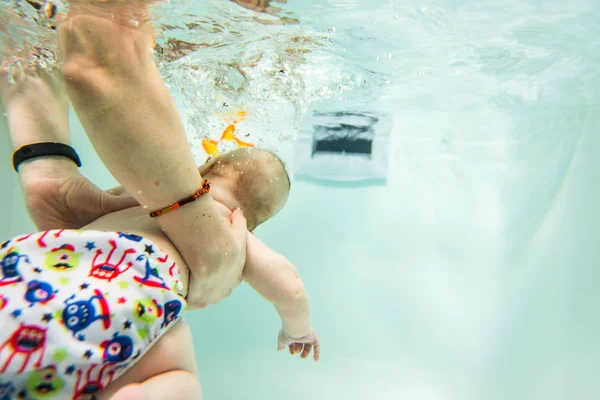 Ein kleines Kind schwimmt unter Wasser. Das Baby ist mit Tauchen beschäftigt. — Stockfoto