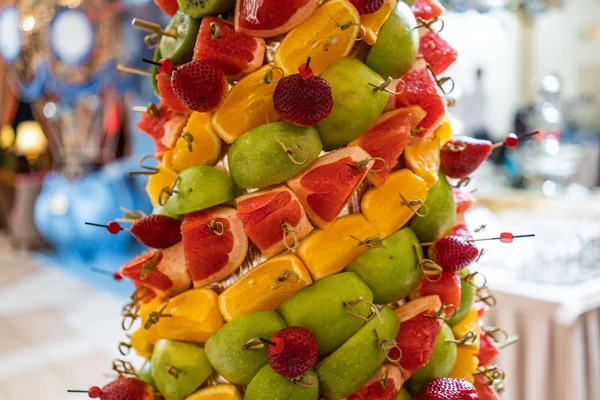 Tropical fruits cut thtower of chopped tropical fruits and strawberries at the Banquet. appetizer at the Banquet. dessert. fruit toweran Fruit Tower with pineapple Royalty Free Stock Images
