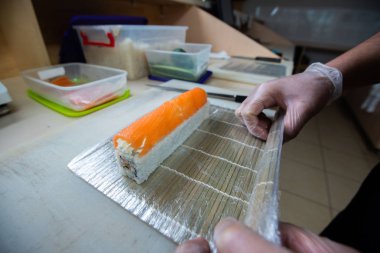 Japon suşisi yapan el yapımı bir aşçı. Japon şef işteki lezzetli suşi rulosunu yılan balığı ve avokado ile hazırlıyor. Japon yemekleri iştah açıcı..