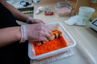 Japon suşisi yapan el yapımı bir aşçı. Japon şef işteki lezzetli suşi rulosunu yılan balığı ve avokado ile hazırlıyor. Japon yemekleri iştah açıcı..