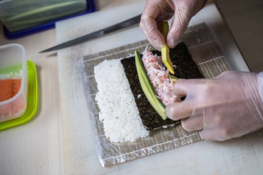 Japon suşisi yapan el yapımı bir aşçı. Japon şef işteki lezzetli suşi rulosunu yılan balığı ve avokado ile hazırlıyor. Japon yemekleri iştah açıcı..
