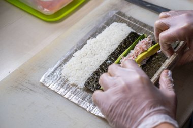 Japon suşisi yapan el yapımı bir aşçı. Japon şef işteki lezzetli suşi rulosunu yılan balığı ve avokado ile hazırlıyor. Japon yemekleri iştah açıcı..