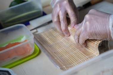 Japon suşisi yapan el yapımı bir aşçı. Japon şef işteki lezzetli suşi rulosunu yılan balığı ve avokado ile hazırlıyor. Japon yemekleri iştah açıcı..