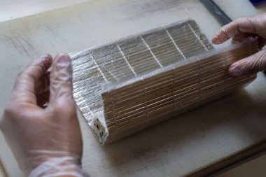 Japon suşisi yapan el yapımı bir aşçı. Japon şef işteki lezzetli suşi rulosunu yılan balığı ve avokado ile hazırlıyor. Japon yemekleri iştah açıcı..