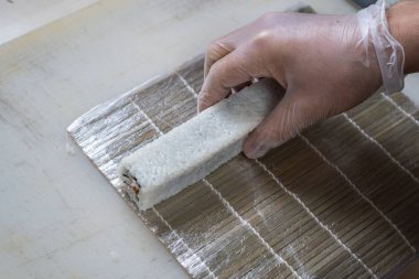 Japon suşisi yapan el yapımı bir aşçı. Japon şef işteki lezzetli suşi rulosunu yılan balığı ve avokado ile hazırlıyor. Japon yemekleri iştah açıcı..