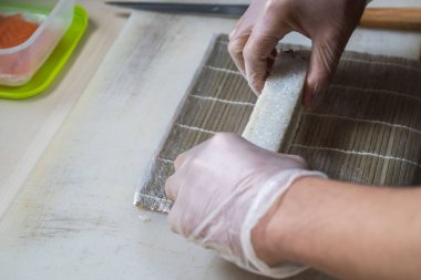 Japon suşisi yapan el yapımı bir aşçı. Japon şef işteki lezzetli suşi rulosunu yılan balığı ve avokado ile hazırlıyor. Japon yemekleri iştah açıcı..