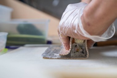 Japon suşisi yapan el yapımı bir aşçı. Japon şef işteki lezzetli suşi rulosunu yılan balığı ve avokado ile hazırlıyor. Japon yemekleri iştah açıcı..