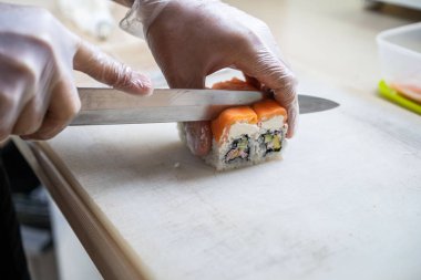 Japon suşisi yapan el yapımı bir aşçı. Japon şef işteki lezzetli suşi rulosunu yılan balığı ve avokado ile hazırlıyor. Japon yemekleri iştah açıcı..