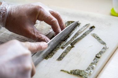 Japon suşisi yapan el yapımı bir aşçı. Japon şef işteki lezzetli suşi rulosunu yılan balığı ve avokado ile hazırlıyor. Japon yemekleri iştah açıcı..