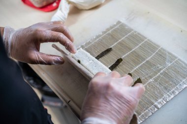 Japon suşisi yapan el yapımı bir aşçı. Japon şef işteki lezzetli suşi rulosunu yılan balığı ve avokado ile hazırlıyor. Japon yemekleri iştah açıcı..