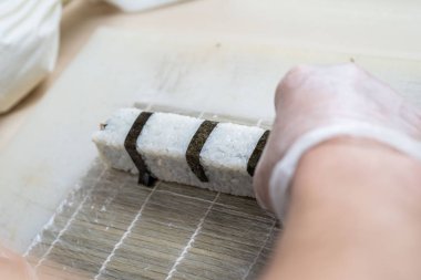 Japon suşisi yapan el yapımı bir aşçı. Japon şef işteki lezzetli suşi rulosunu yılan balığı ve avokado ile hazırlıyor. Japon yemekleri iştah açıcı..