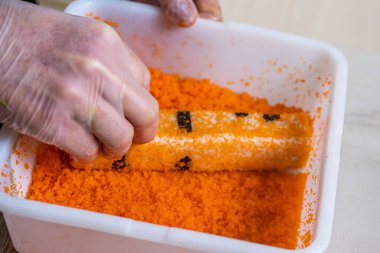 Japon suşisi yapan el yapımı bir aşçı. Japon şef işteki lezzetli suşi rulosunu yılan balığı ve avokado ile hazırlıyor. Japon yemekleri iştah açıcı..