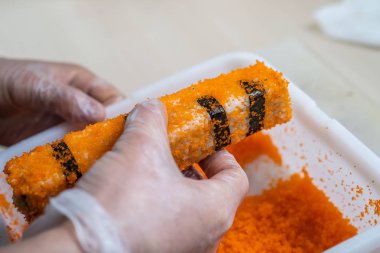 Japon suşisi yapan el yapımı bir aşçı. Japon şef işteki lezzetli suşi rulosunu yılan balığı ve avokado ile hazırlıyor. Japon yemekleri iştah açıcı..