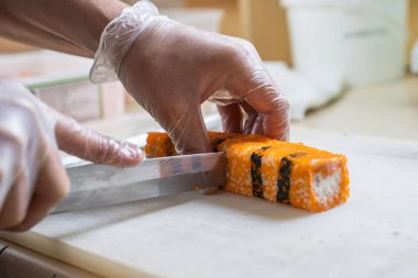 Japon suşisi yapan el yapımı bir aşçı. Japon şef işteki lezzetli suşi rulosunu yılan balığı ve avokado ile hazırlıyor. Japon yemekleri iştah açıcı..