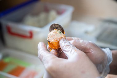 Japon suşisi yapan el yapımı bir aşçı. Japon şef işteki lezzetli suşi rulosunu yılan balığı ve avokado ile hazırlıyor. Japon yemekleri iştah açıcı..