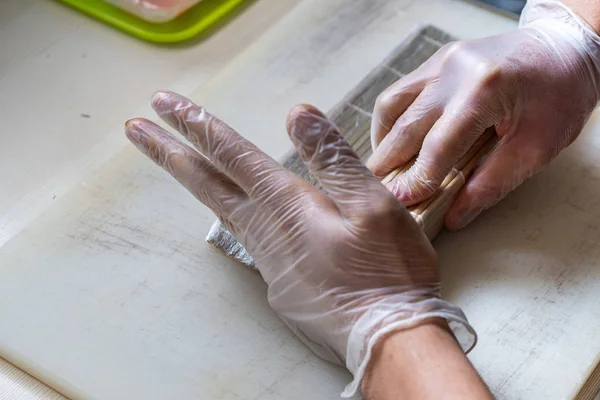 Cook hands making japanese sushi roll. Japanese chef at work preparing delicious sushi roll with eel and avocado. Appetizing japanese food.