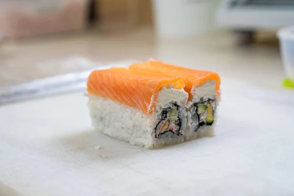 A szakácsok japán sushi tekercset készítenek. A japán séf finom sushi tekercset készít angolnával és avokádóval. Étvágygerjesztő japán étel. — Stock Fotó