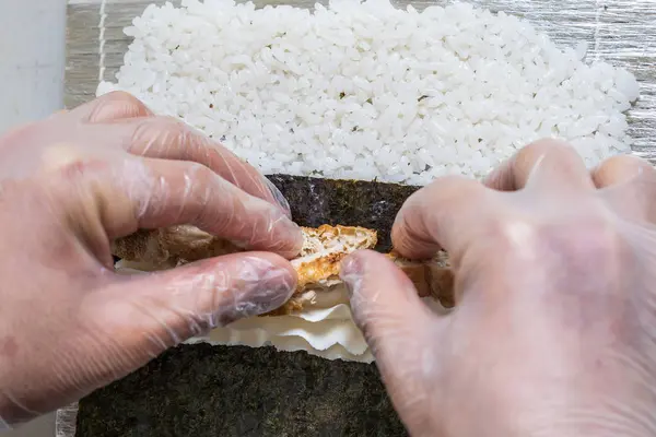 손으로 일본스 시 롤만들기. 일본 요리사는 직장에서 뱀장어와 아보카도와 함께 맛있는 초밥 롤을 준비 한다. 일본 음식을 주문하는 모습. — 스톡 사진