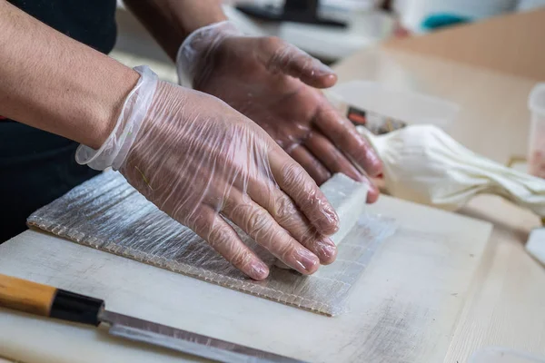 Cocinar las manos haciendo rollo de sushi japonés. Chef japonés en el trabajo preparando delicioso rollo de sushi con anguila y aguacate. Apetitivo comida japonesa. — Foto de Stock