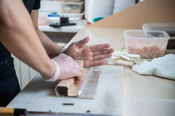 Cozinhe as mãos fazendo rolo de sushi japonês. chef japonês no trabalho preparando delicioso rolo de sushi com enguia e abacate. Comida japonesa apetitosa. — Fotografia de Stock